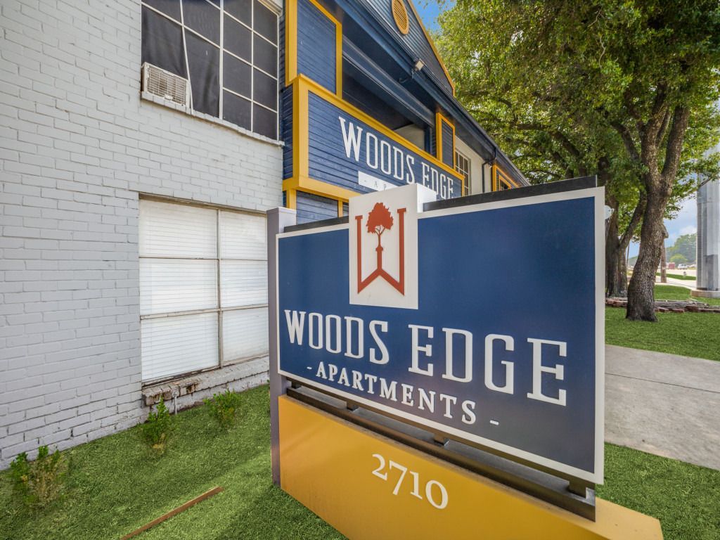 A sign for woods edge apartments is outside of a building