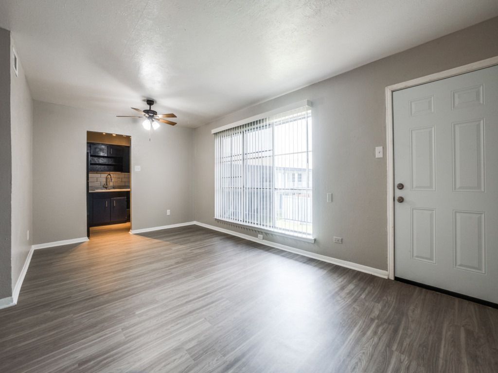 An empty living room with hardwood floors and a ceiling fan.