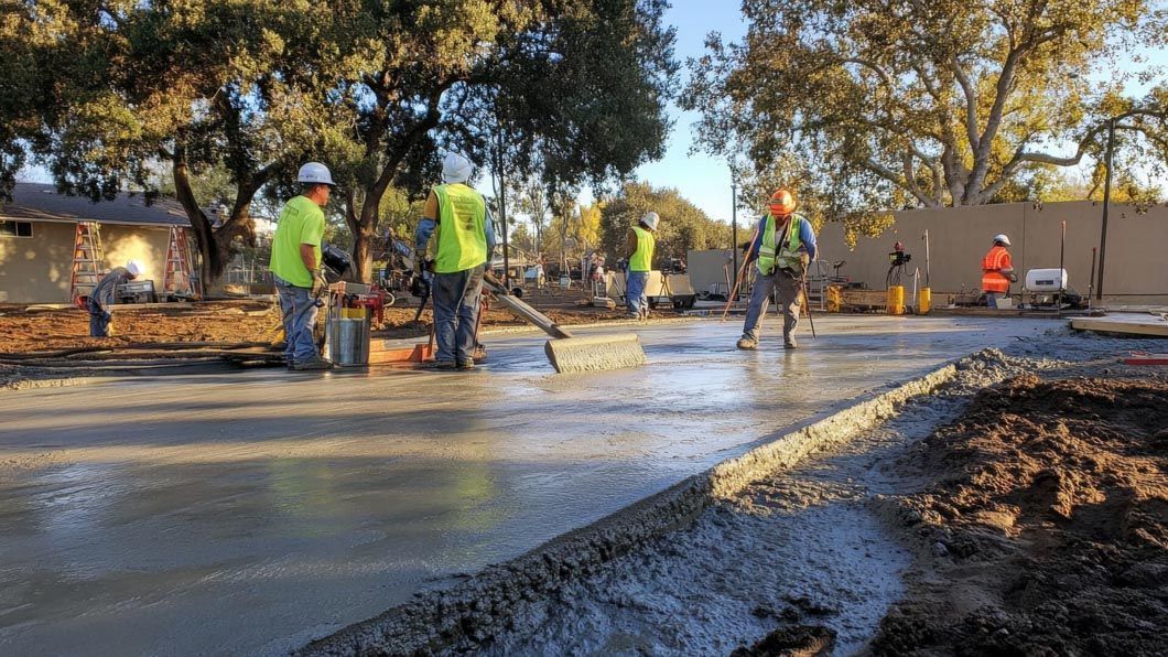 A group of construction workers are working on a concrete floor.