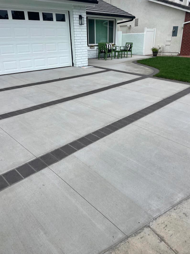 A concrete driveway in front of a house with a white garage door.