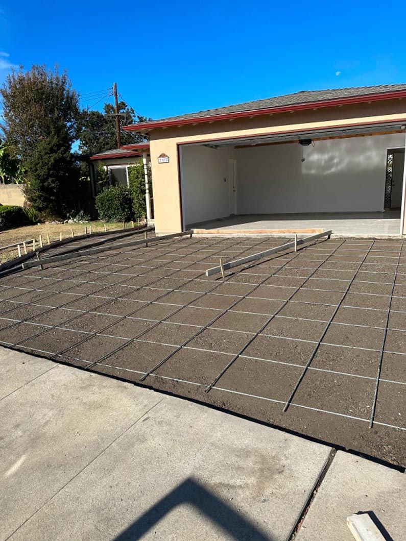 A concrete driveway is being built in front of a garage.