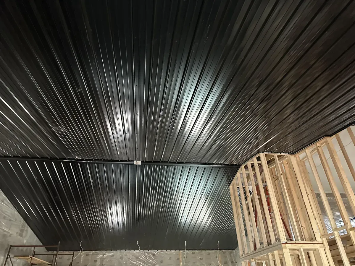 Black corrugated ceiling with a bright light, above a stack of wooden pallets in a warehouse