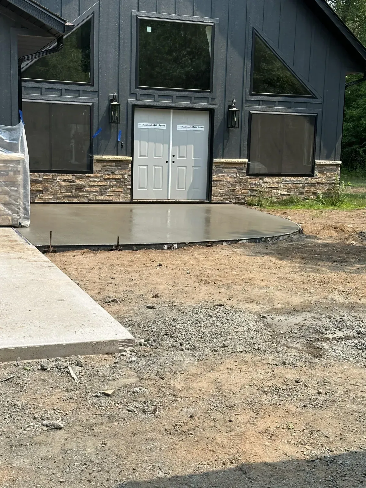 Front entrance of a dark building with white double doors, concrete stoop, and gravel foreground.