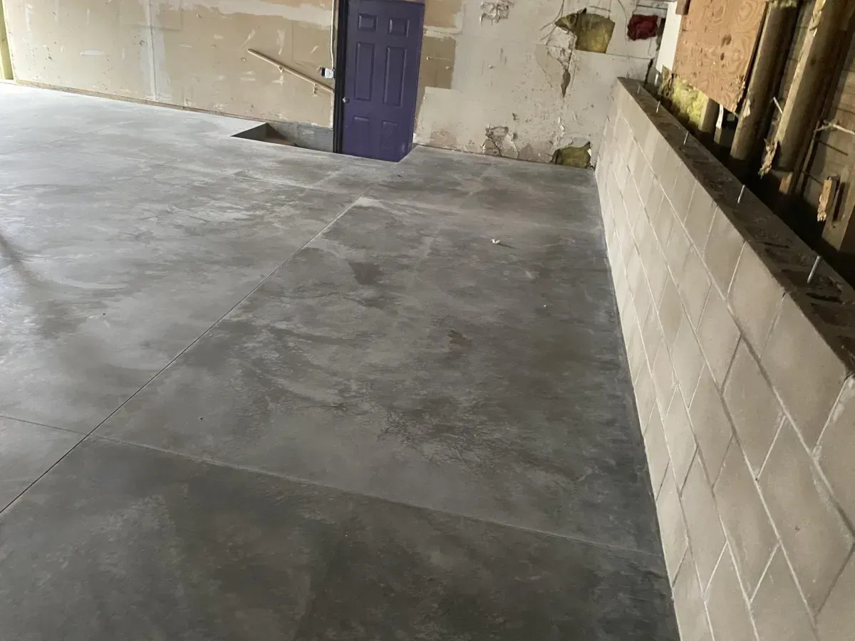Empty concrete garage with a purple door and cinder block wall
