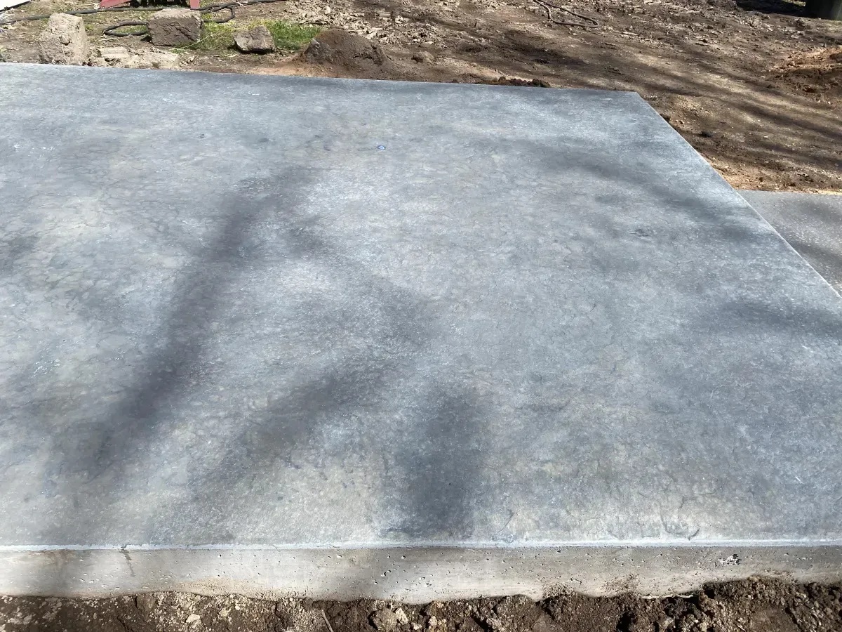 Empty concrete slab outdoors with dappled tree shadows around it