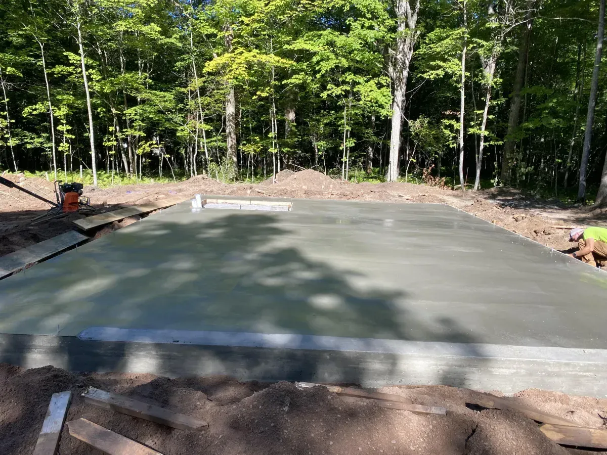 Freshly poured concrete slab in a wooded outdoor construction site