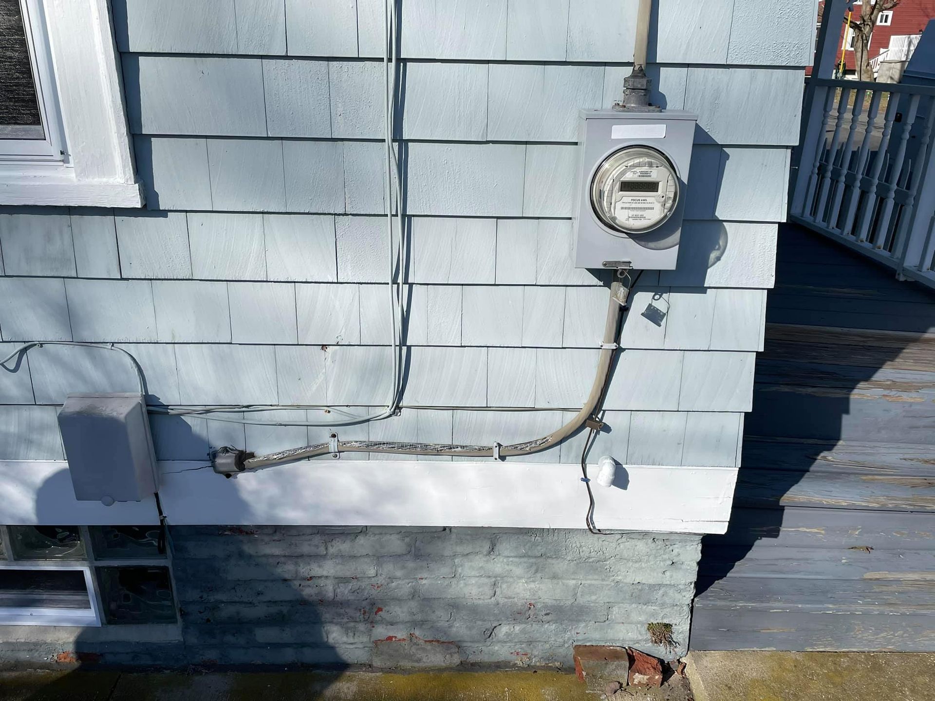 Light blue siding with an electric meter and conduit.