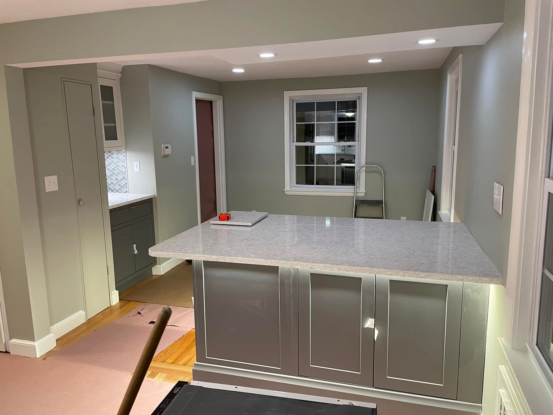 Kitchen renovation with gray cabinets, white countertop, and sage green walls.