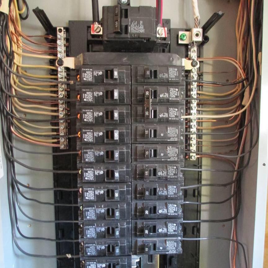 Electrical panel with numerous circuit breakers and wires.