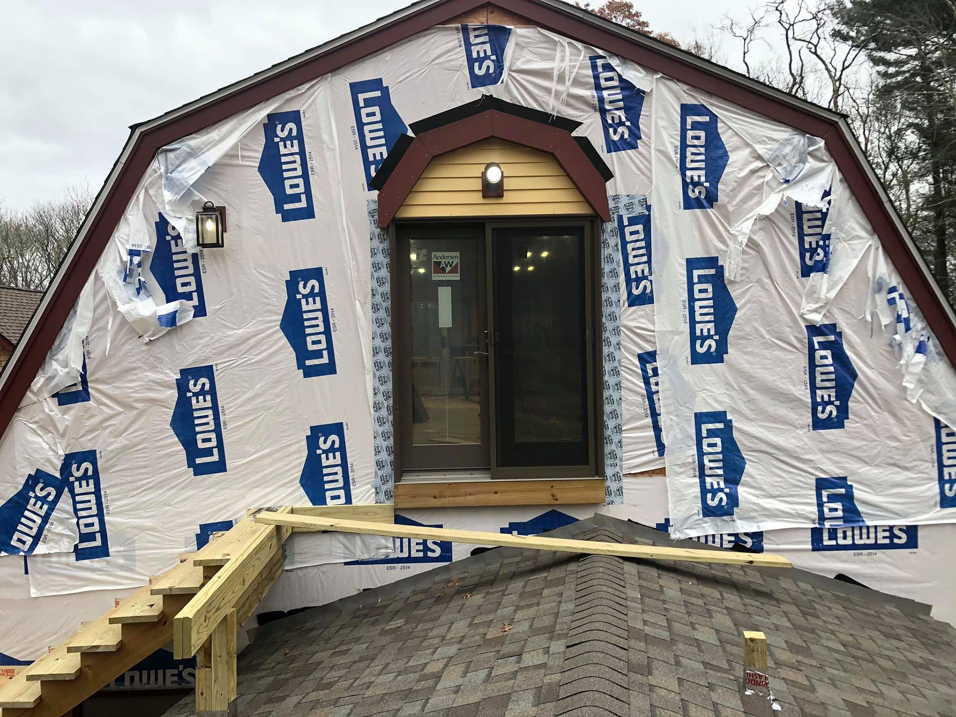 Building exterior with a door and temporary stairs covered in Lowe's branded wrap.