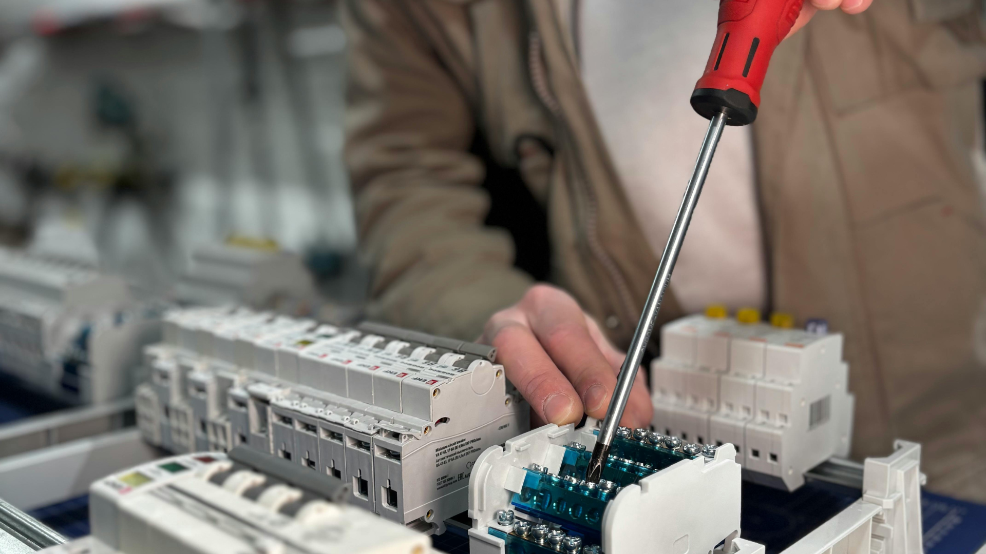 Person using a screwdriver on electrical components, indoors.