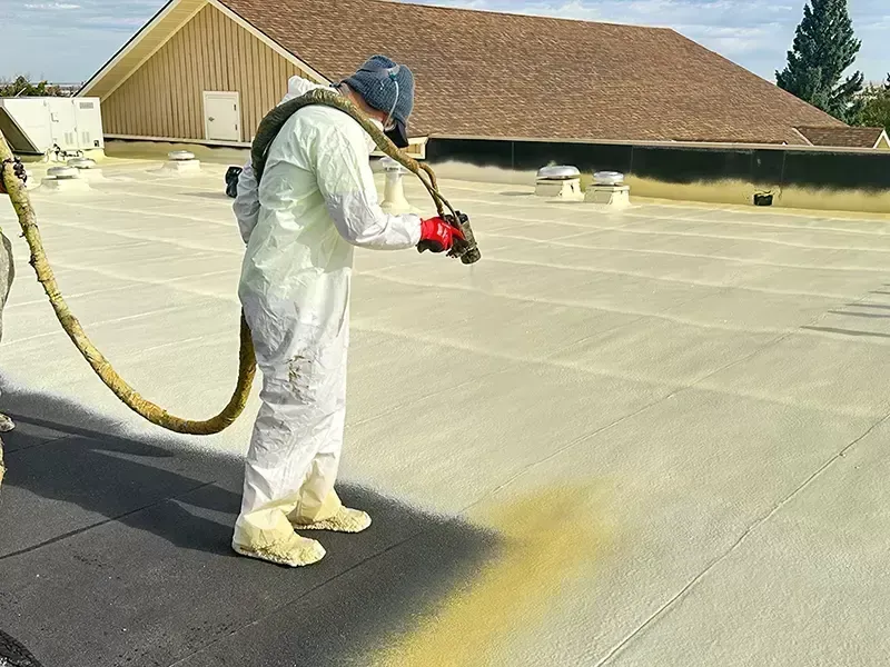 House under construction with exposed roof beams, blue sky, clouds.