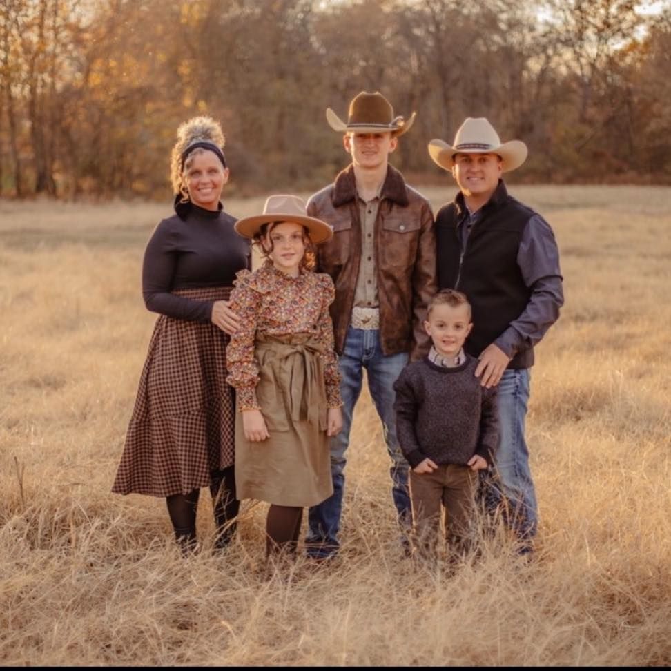 Family of five in a field: mother in skirt, father in vest, teenage son, young daughter, and small boy.