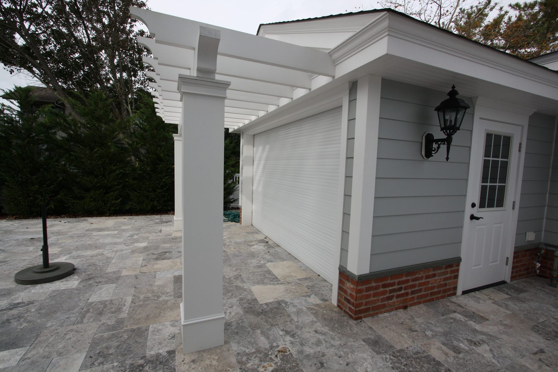 A white garage with a white pergola over it
