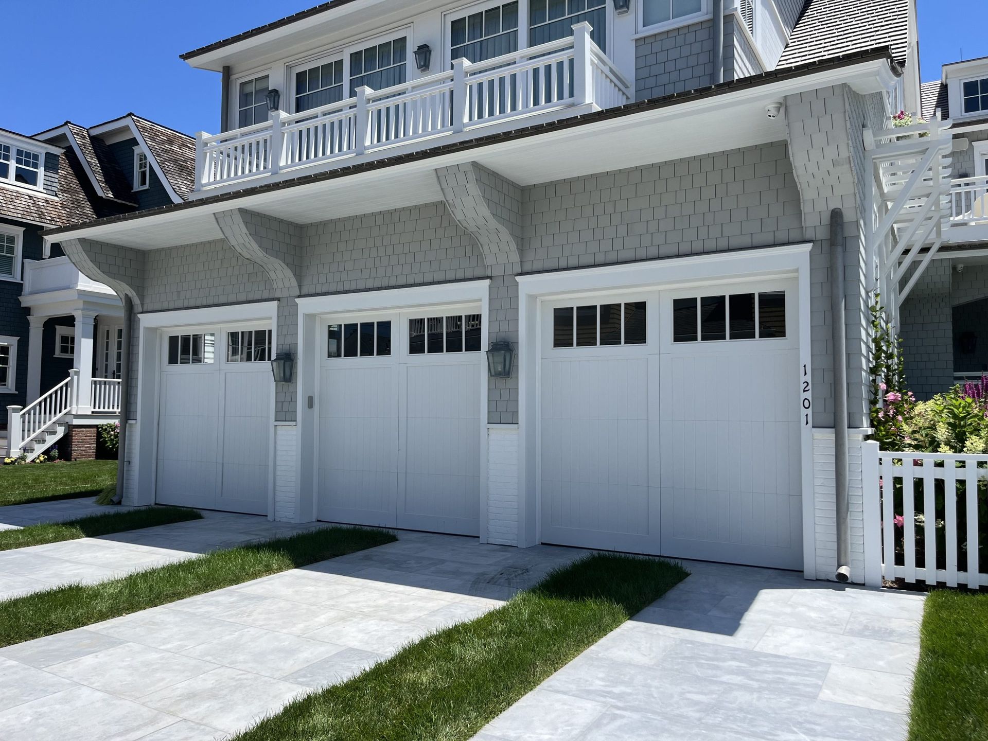 A house with three white garage doors and a white fence