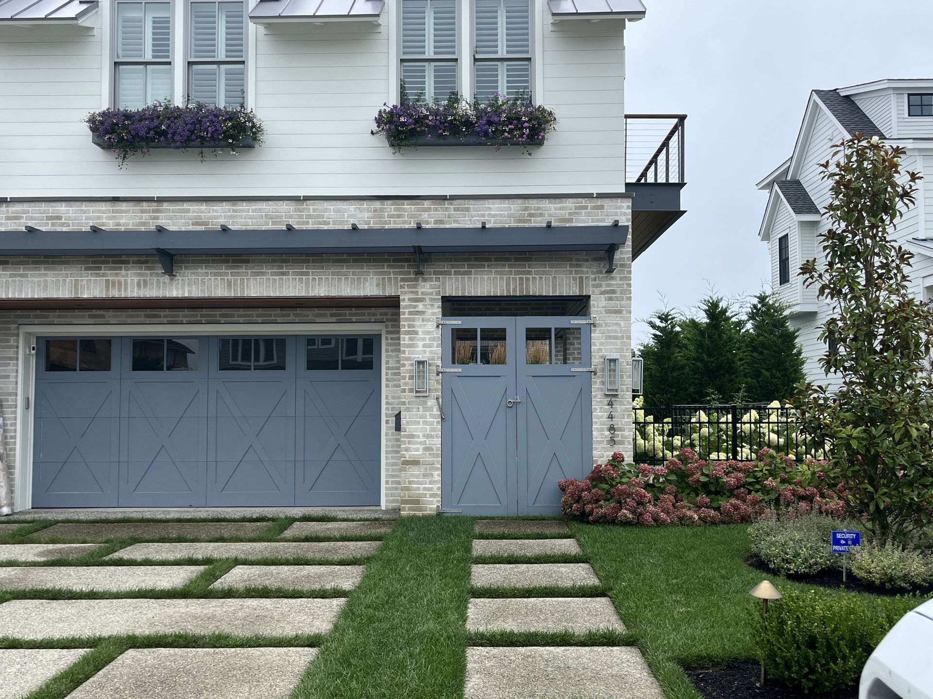 A white house with a blue garage door and a white car parked in front of it.
