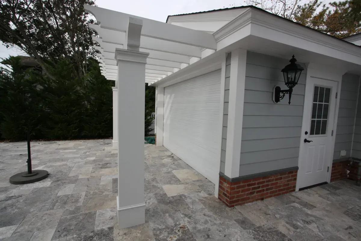 A white garage with a pergola on top of it