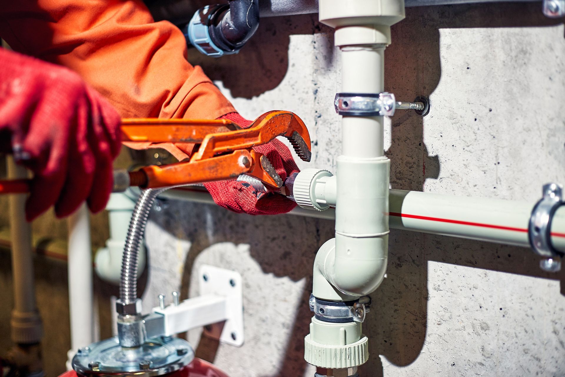 A plumber is working on a pipe with a wrench.