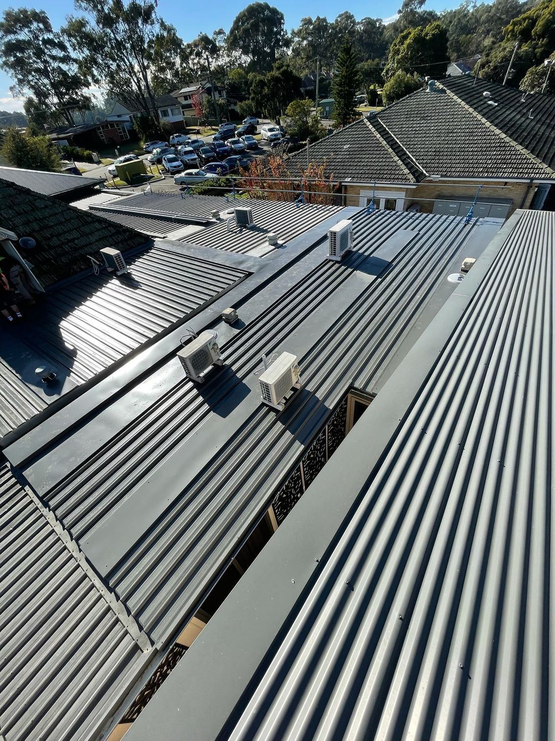 Gray corrugated metal rooftops with air conditioning units, viewed from above.