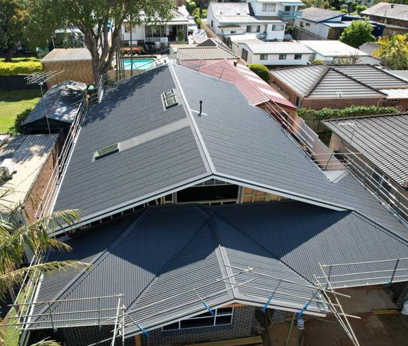 Aerial view of a dark gray metal roof on a residential building with scaffolding around it.