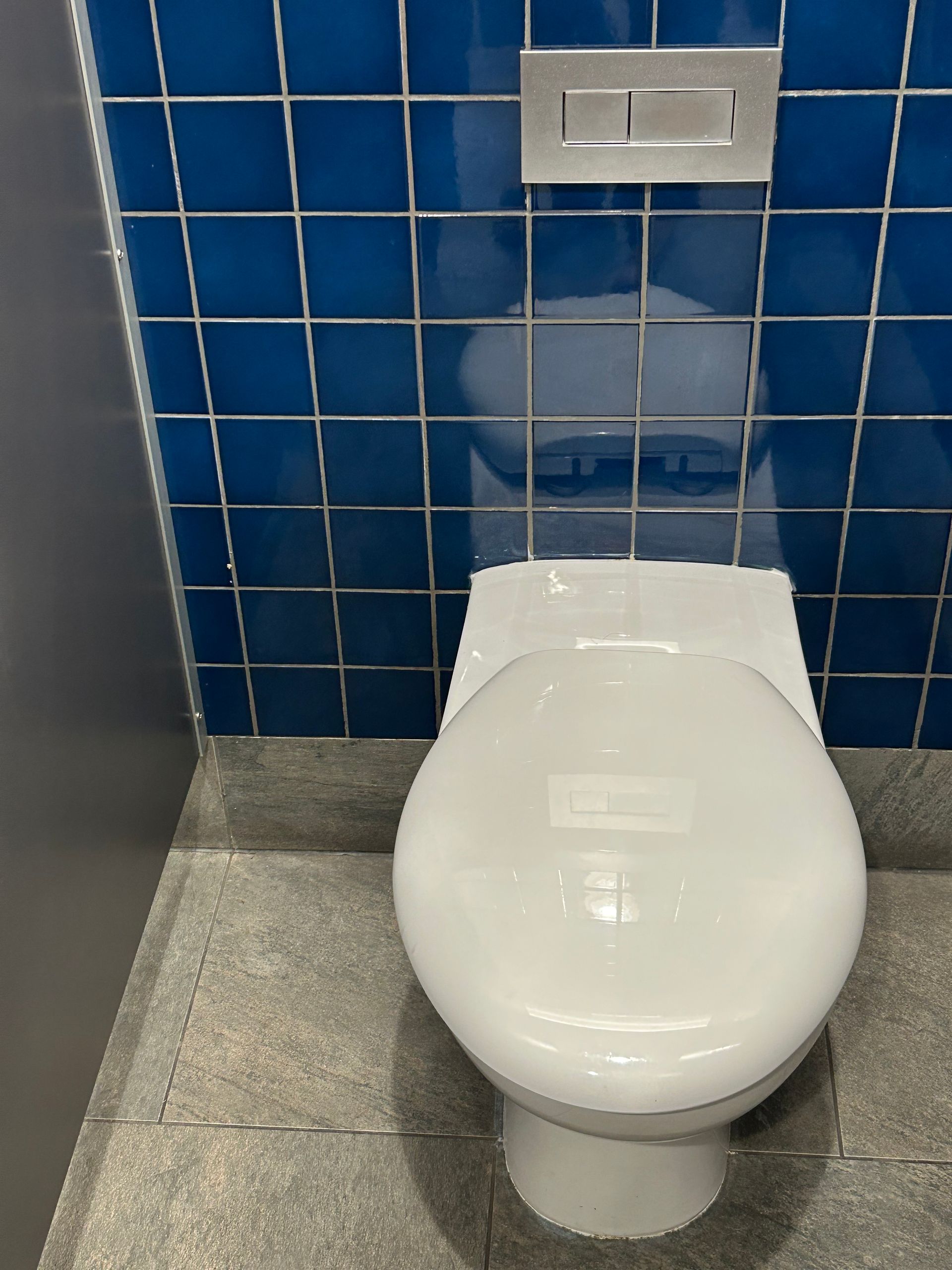 A white toilet in a bathroom with blue tiles