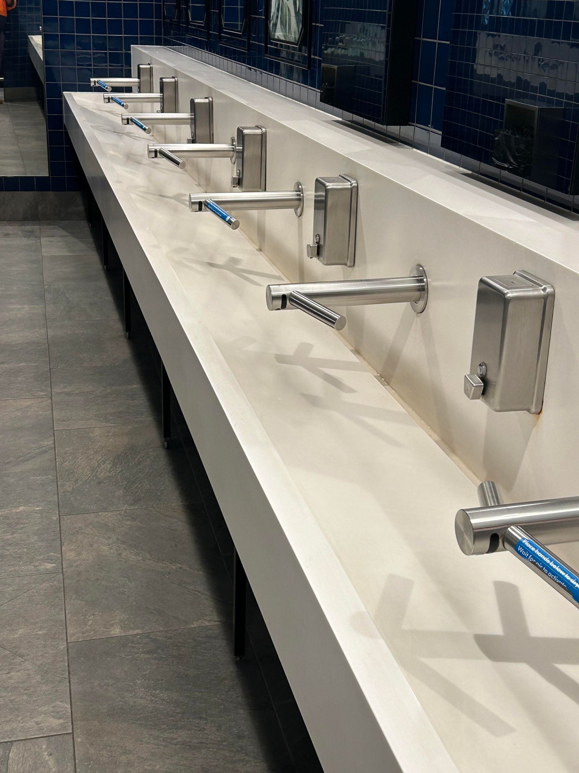 A row of bathroom sinks with toothbrushes on them