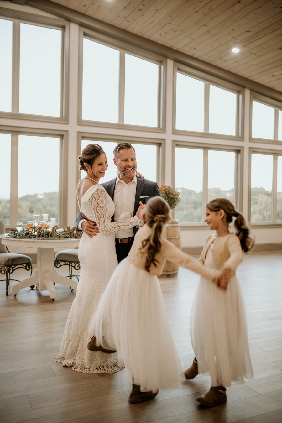 A bride and groom are dancing with their flower girls at their wedding reception.