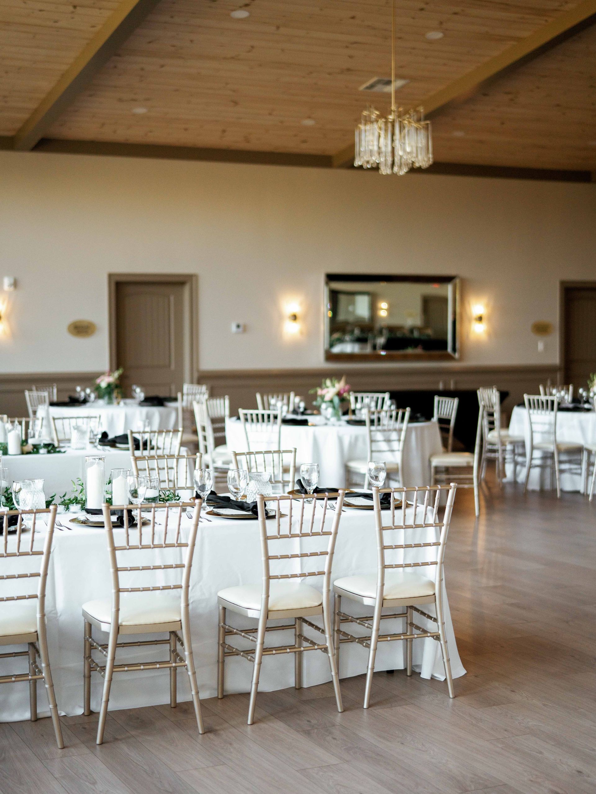 A large room with tables and chairs set up for a wedding reception