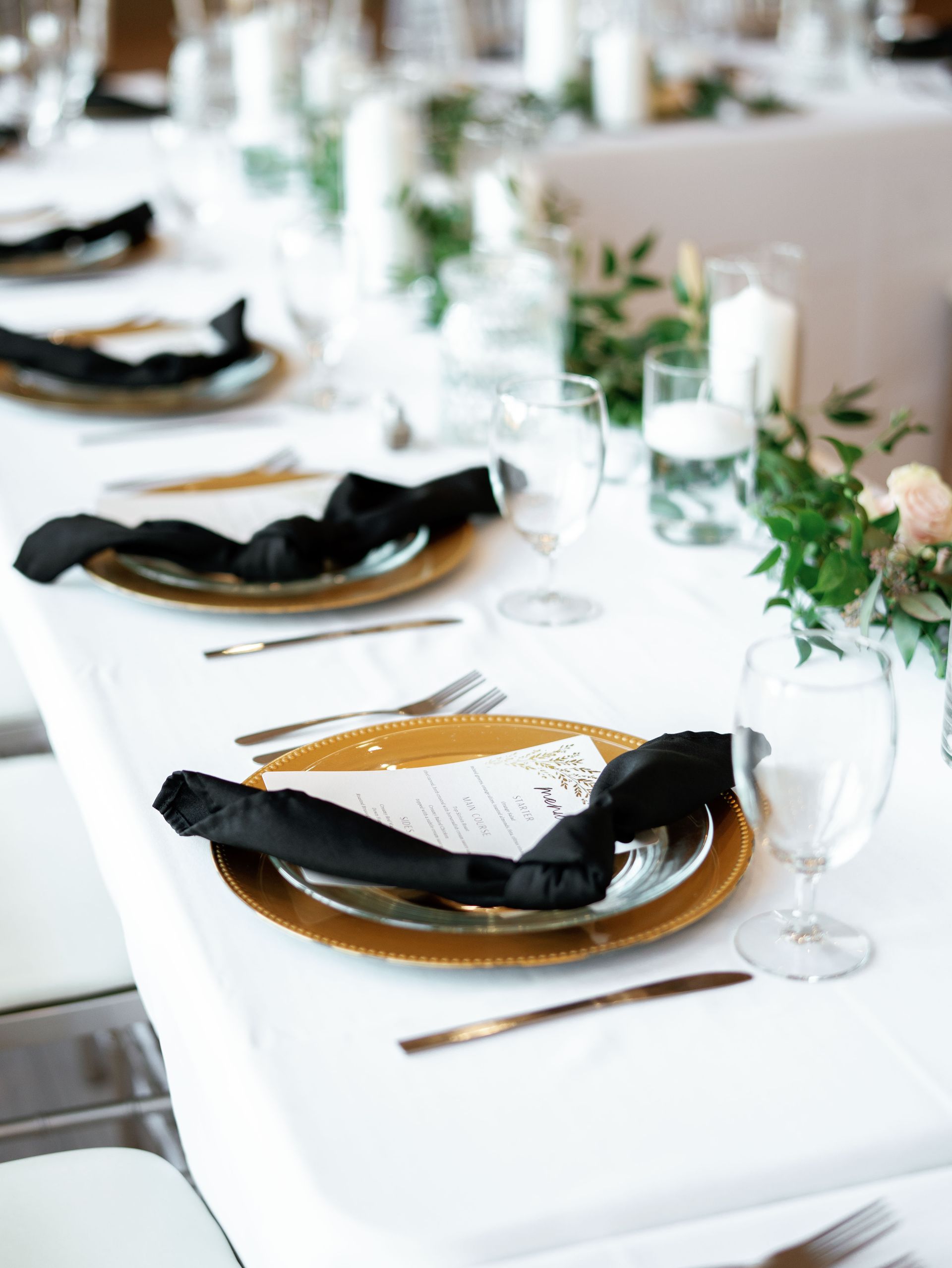 A long table set for a wedding reception with plates , silverware , and candles.