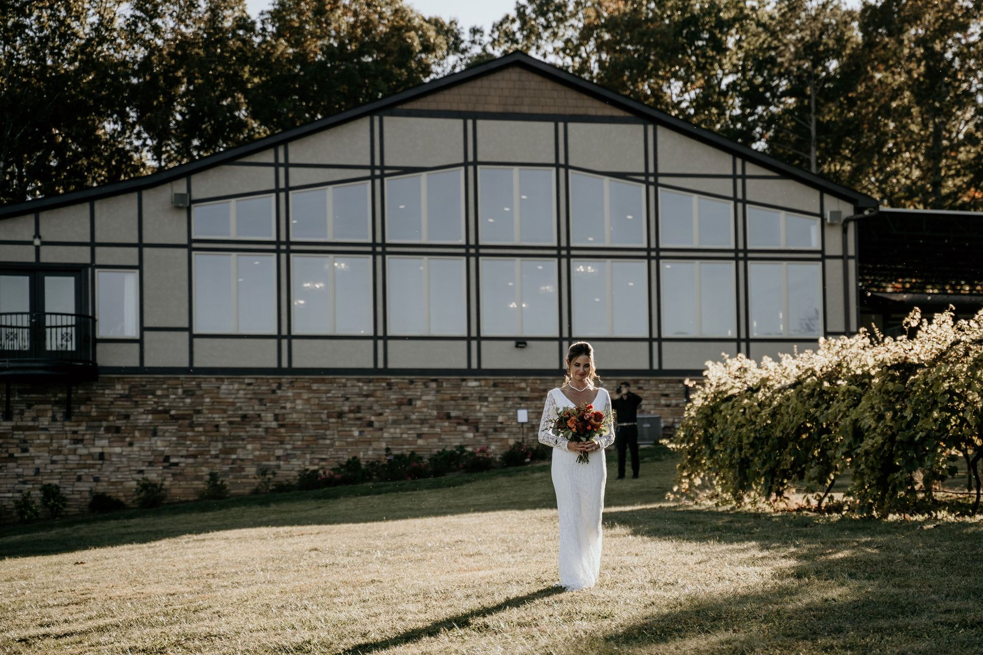 A woman in a white dress is holding a bouquet of flowers in front of a large building.