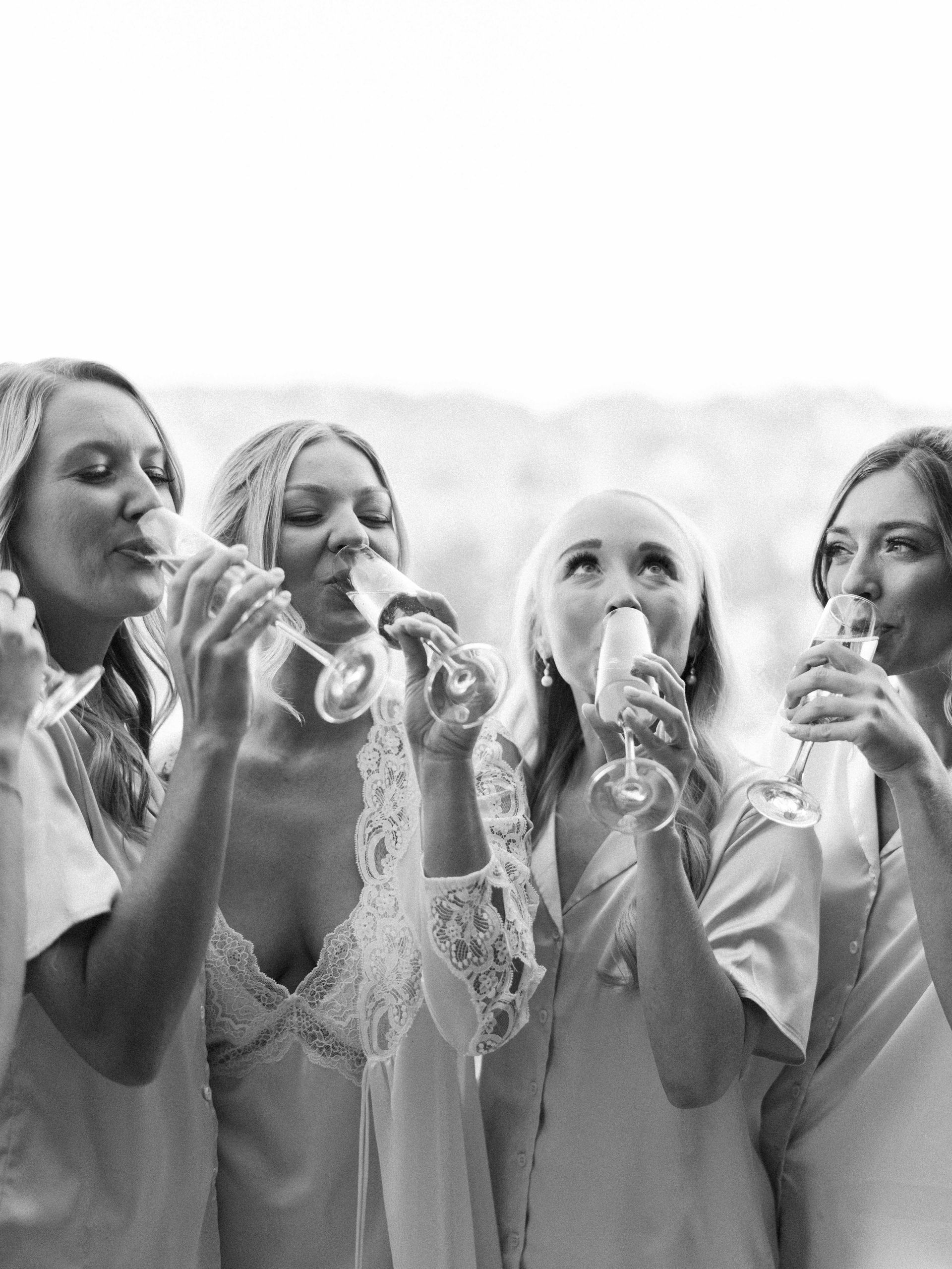 A group of women are drinking champagne together in a black and white photo.