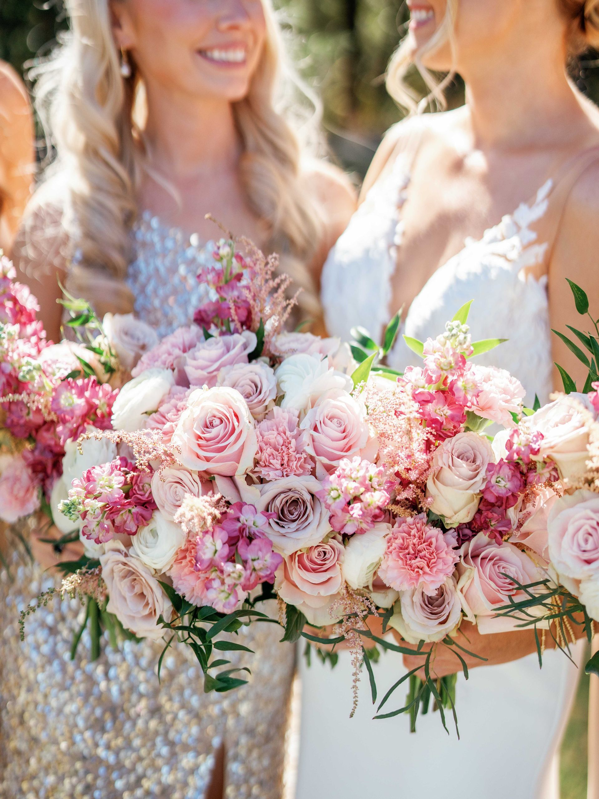 A bride and her bridesmaids are holding bouquets of pink flowers.