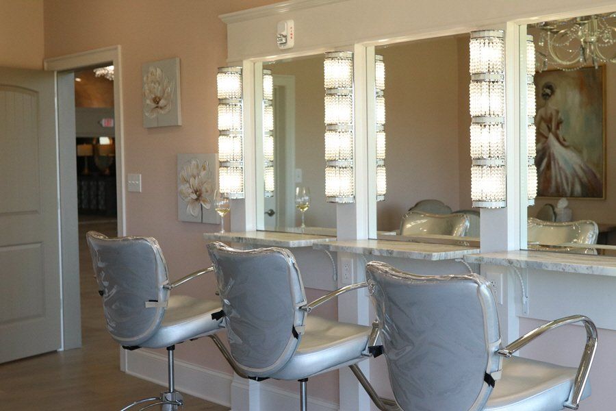 A row of hair salon chairs in front of mirrors