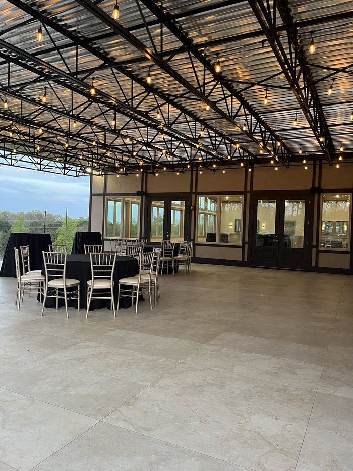 A large room with tables and chairs under a roof