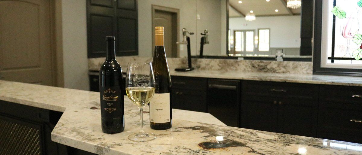 Two bottles of wine and two glasses of wine on a counter