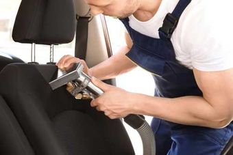 A Man Is Cleaning the Seats of A Car with A Vacuum Cleaner — Townsville Car Care Centre in Aitkenvale, QLD