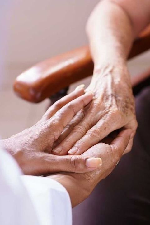 A person is holding another person 's hand while sitting in a chair.