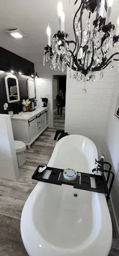 Bathroom with a clawfoot tub, chandelier, and vanity. Someone standing in the hallway.