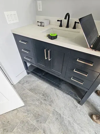 Dark blue bathroom vanity with a white countertop, black faucet, and drawers.