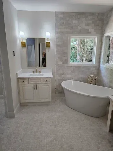 Bathroom with white tub, vanity, and light gray tiled walls.