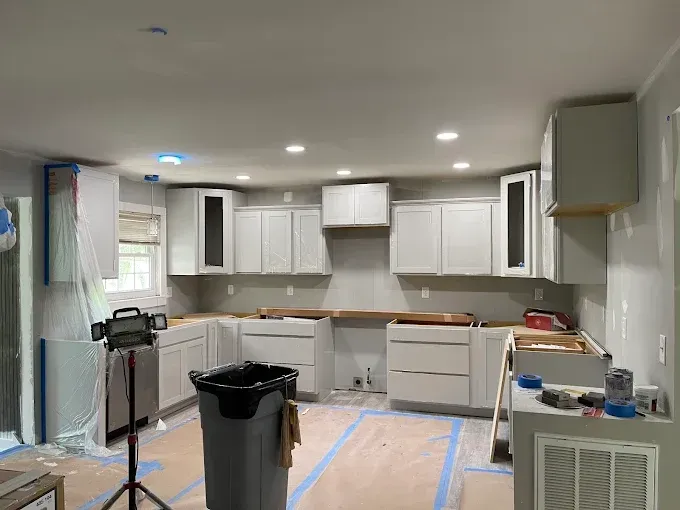 Kitchen remodel in progress, with gray cabinets, countertops, and protective tape on floors.