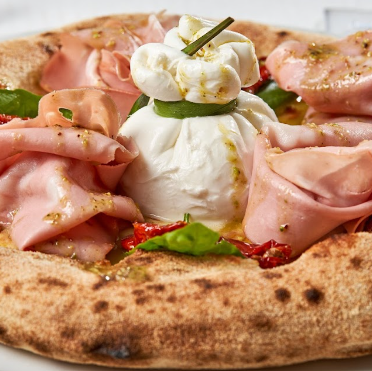 Pizza con mais peperoni olive nere e basilico