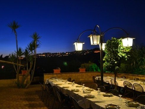 tavolata apparecchiata nella zona esterna del ristorante per una cena 