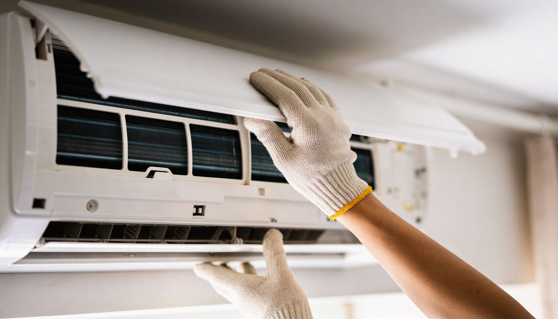 A skilled technician performs indoor air conditioning repair on a mini-split AC unit.