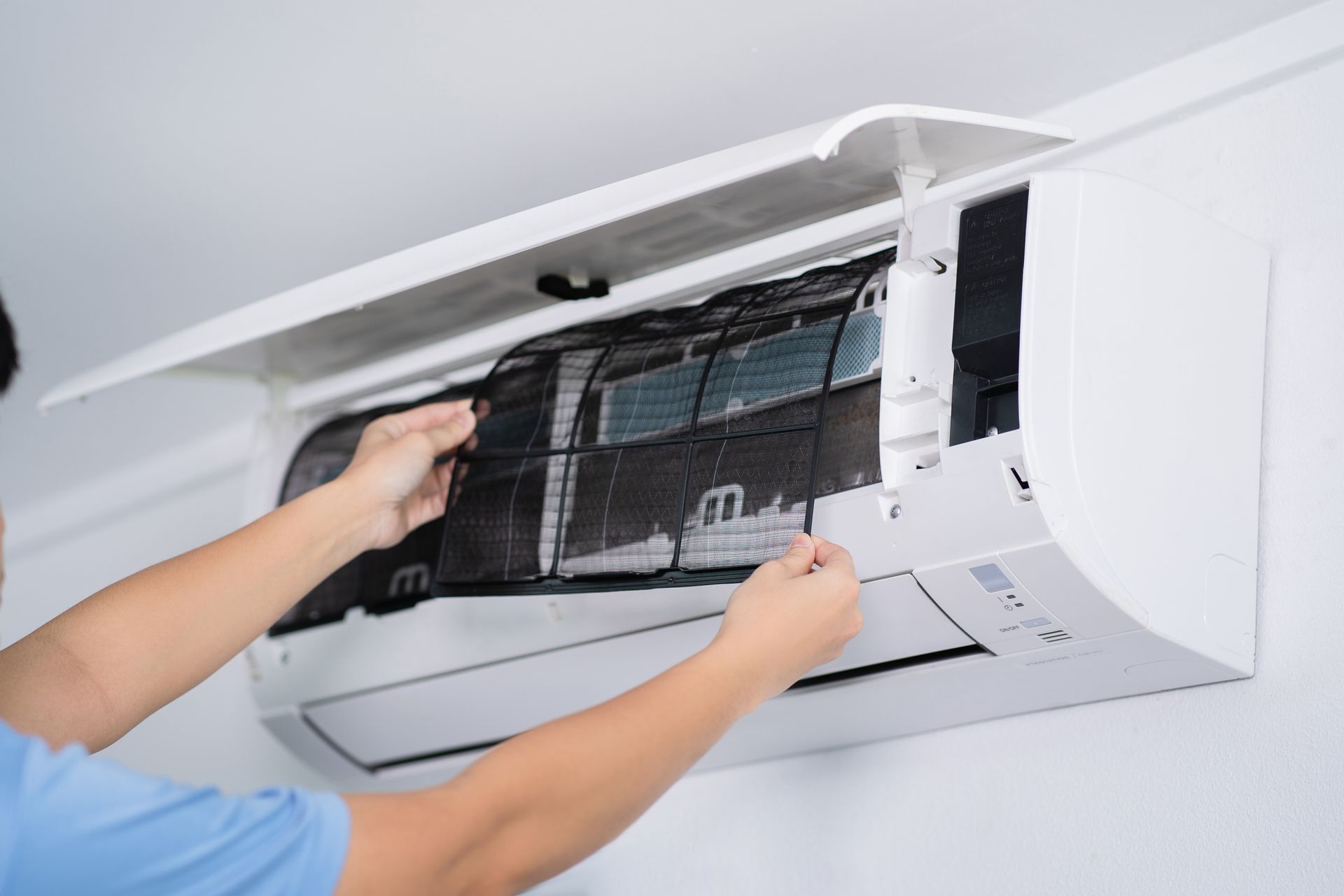 Person cleaning air conditioner filter during routine maintenance.