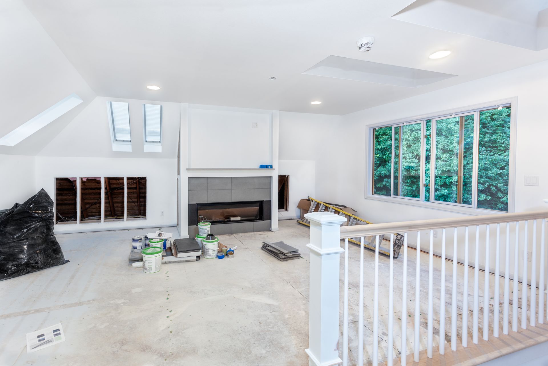 An empty living room with a fireplace and stairs under construction.