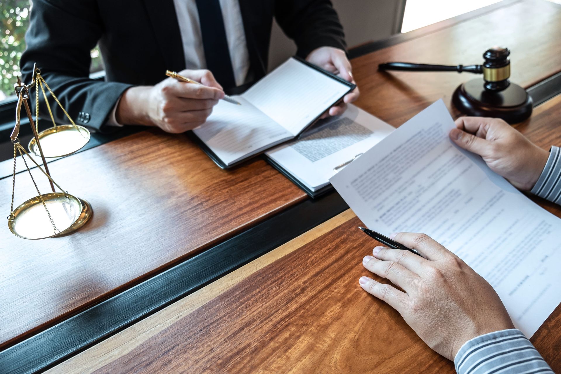Legal professionals reviewing documents at a wooden desk with a gavel and scales of justice nearby
