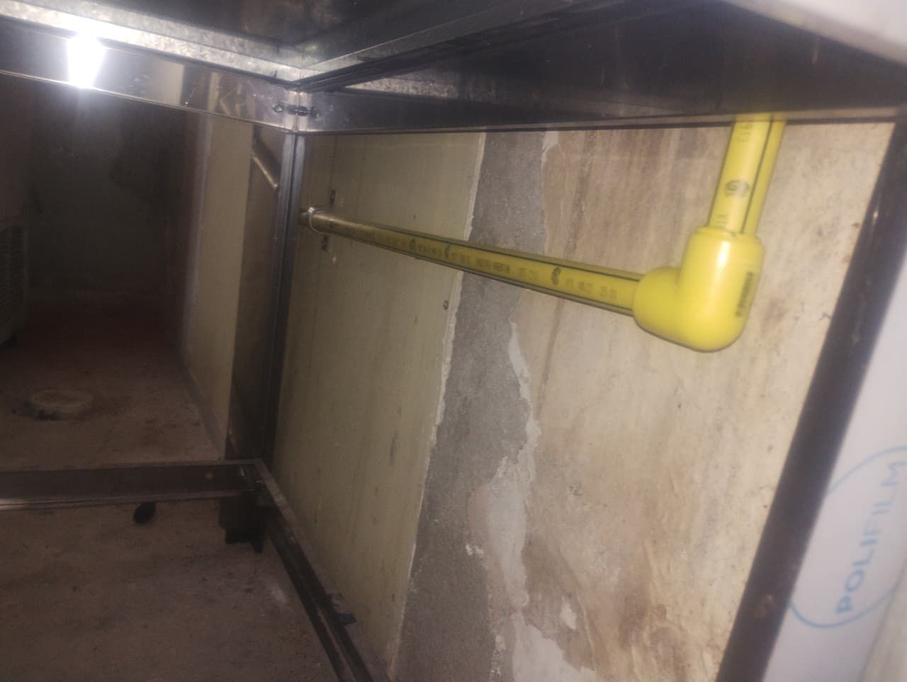 Tubo amarillo que se extiende desde la pared de un armario.