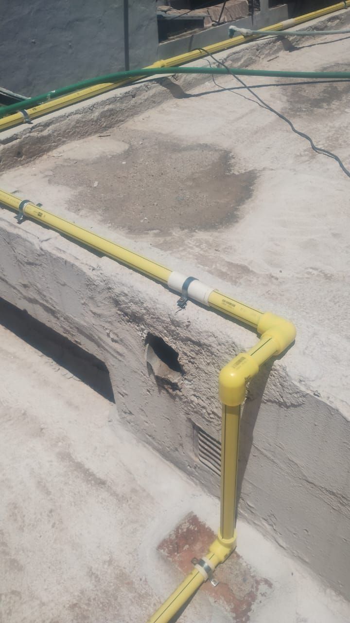 Tuberías de gas amarillas sobre un techo de hormigón. Se aprecia una mancha oscura.