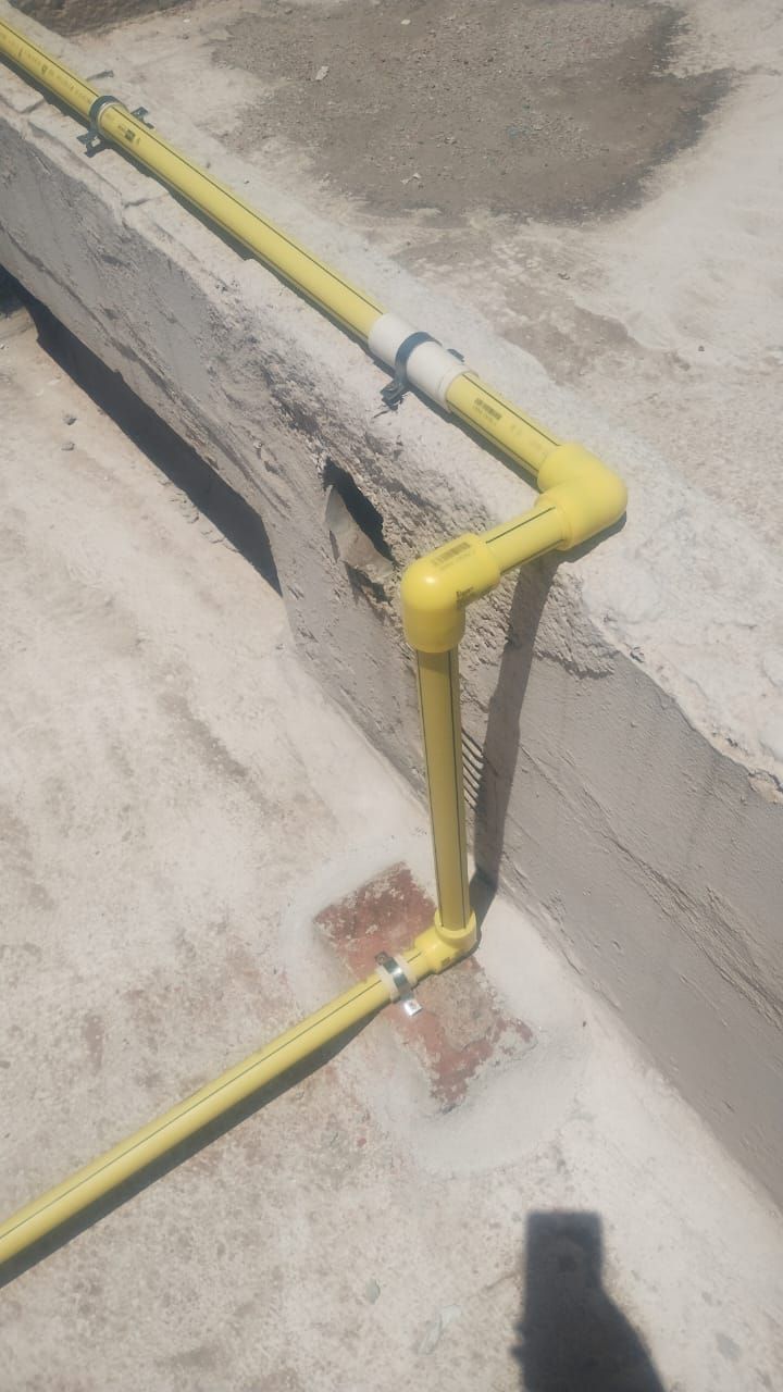 Tuberías de gas amarillas sobre una superficie de hormigón, cerca de una pared.